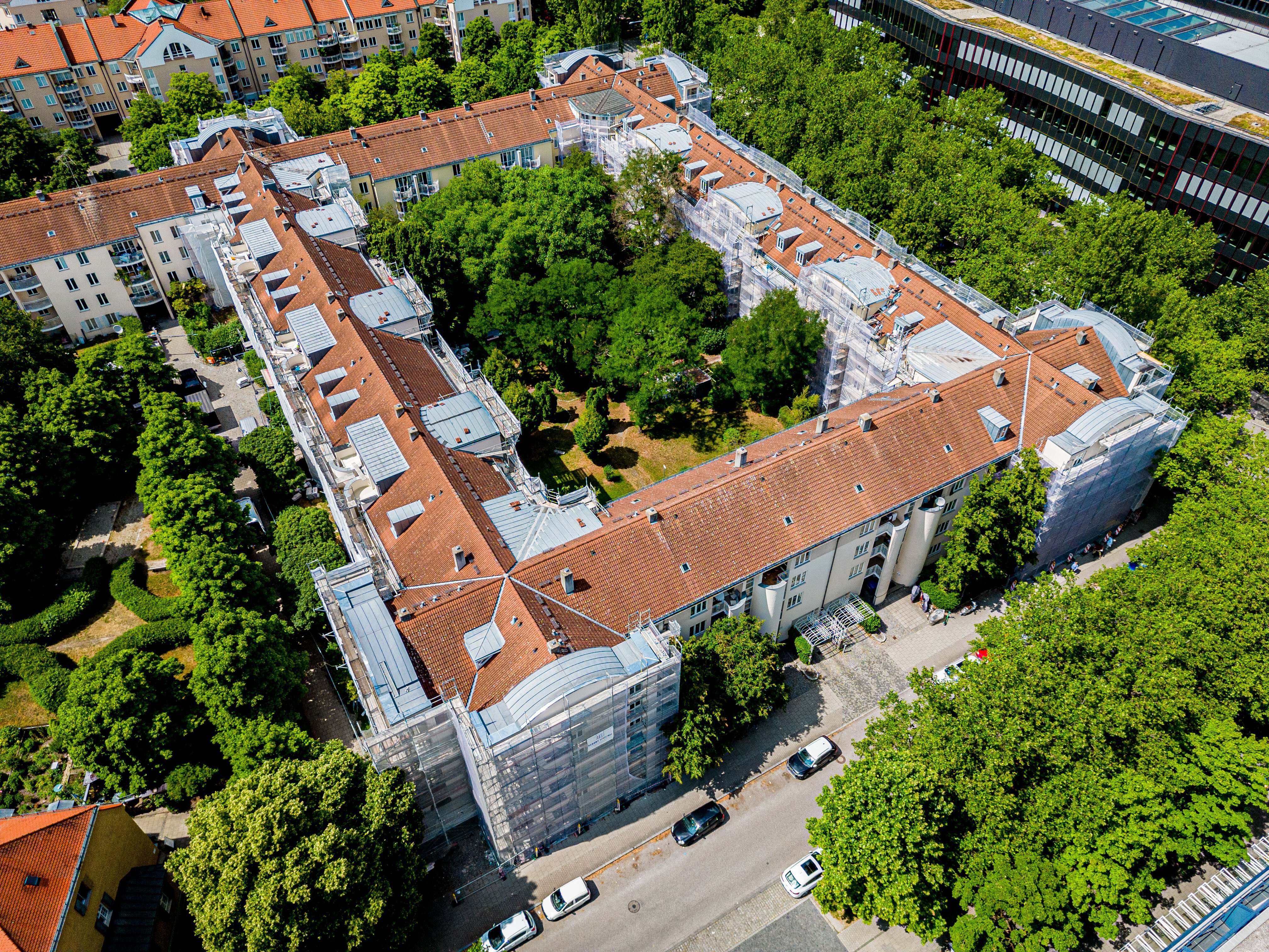 Luftaufnahme des Berliner Quartiers in München mit Gerüsten für den Dachgeschossausbau und die energetische Modernisierung.