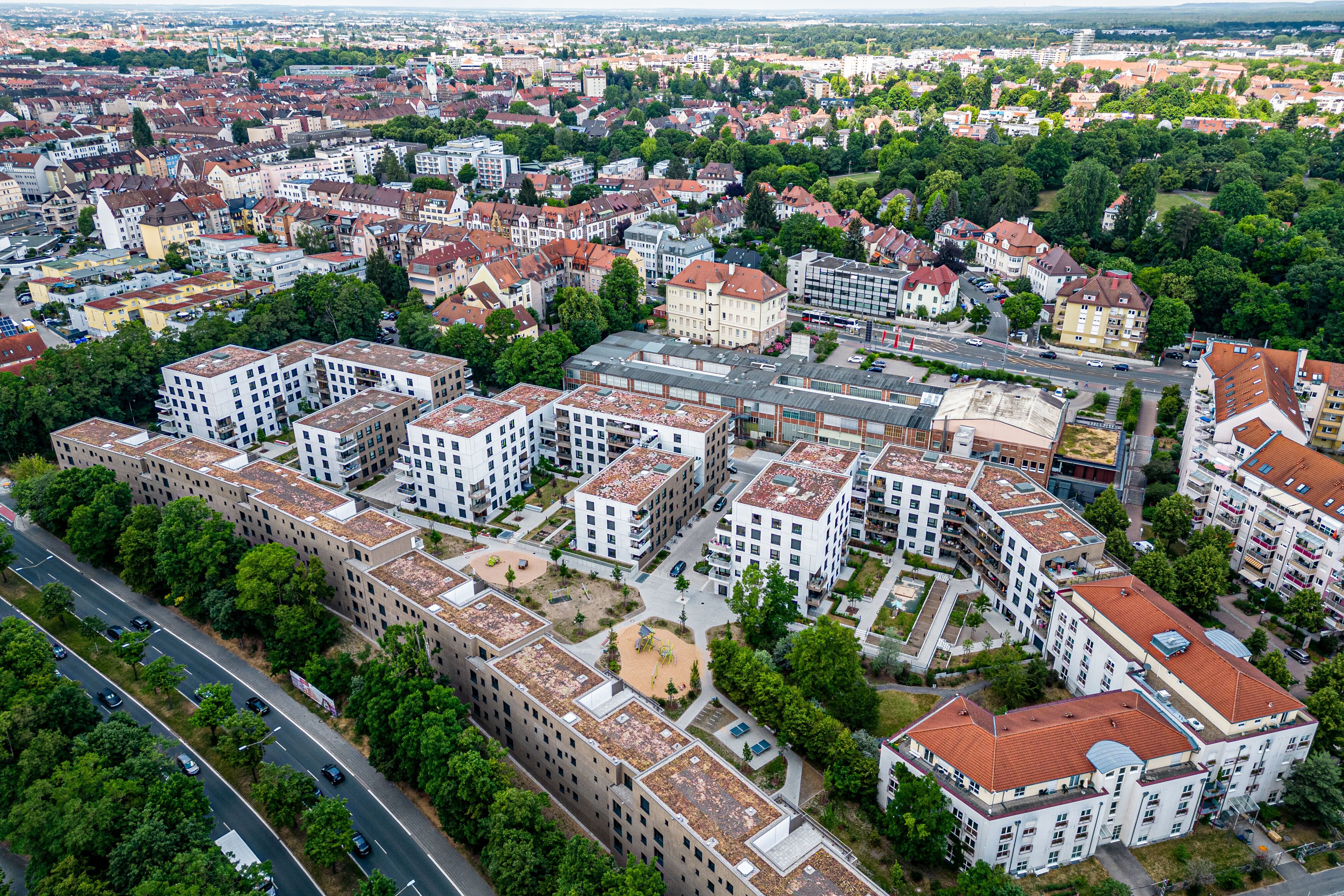 Luftaufnahme des Quartiers Tafel in Nürnberg, zeigt neu errichtete, weiße Wohngebäude, die sich in eine bestehende städtische Umgebung mit Grünflächen einfügen. 