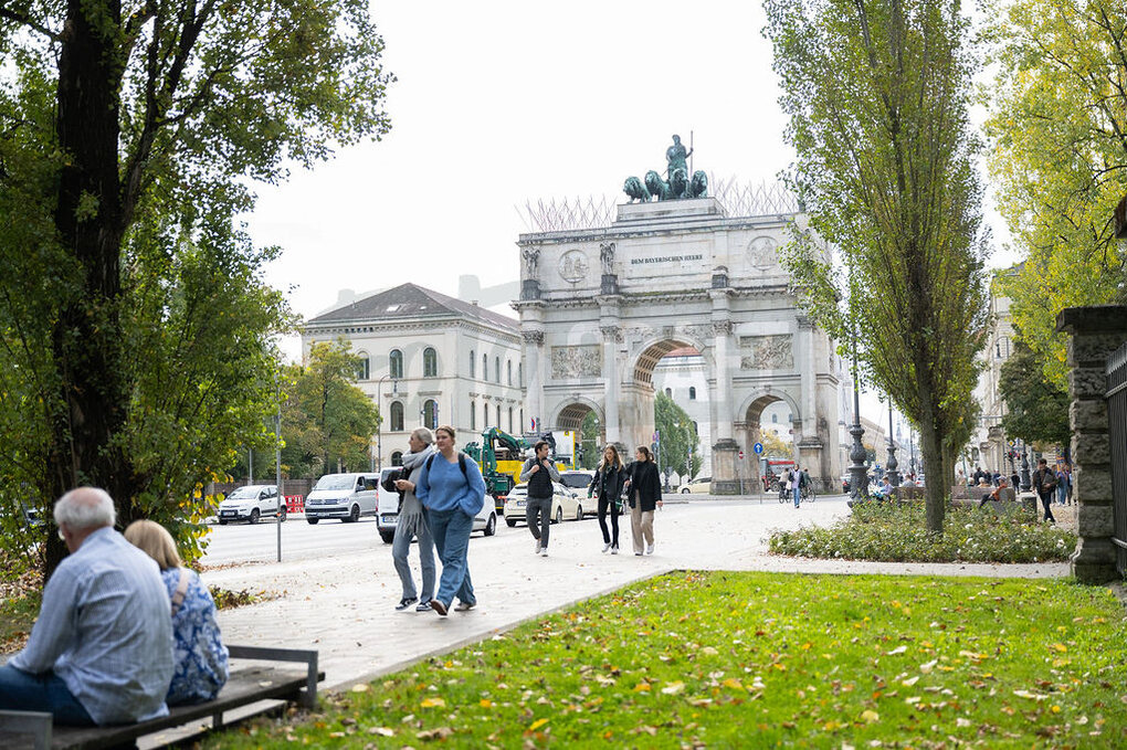 Siegestor München bei Tag mir spazierenden Menschen und Grünanlage