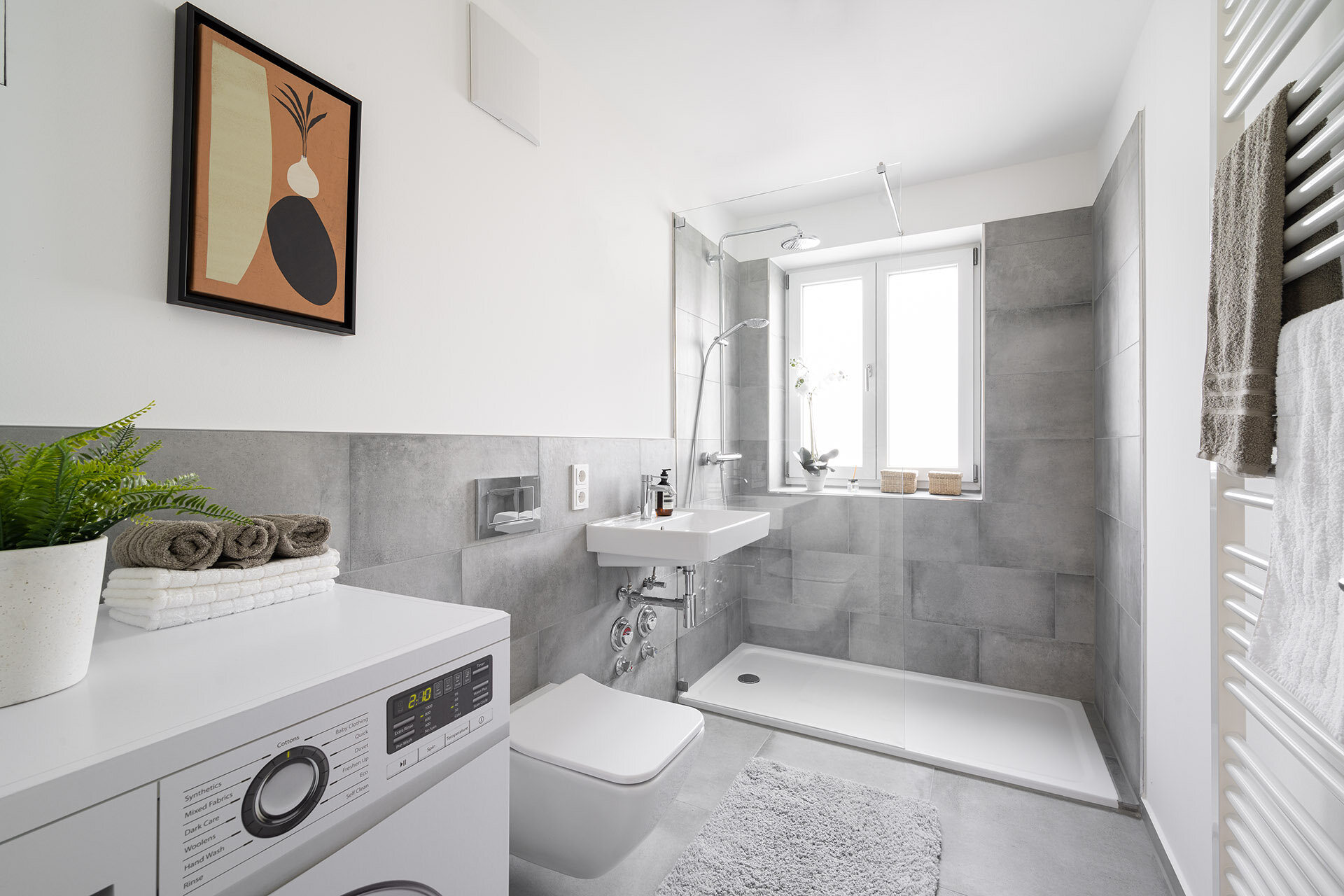 Modernes Badezimmer mit gr0ßer Duschkabine, Toilette, Waschbecken und Waschmaschine