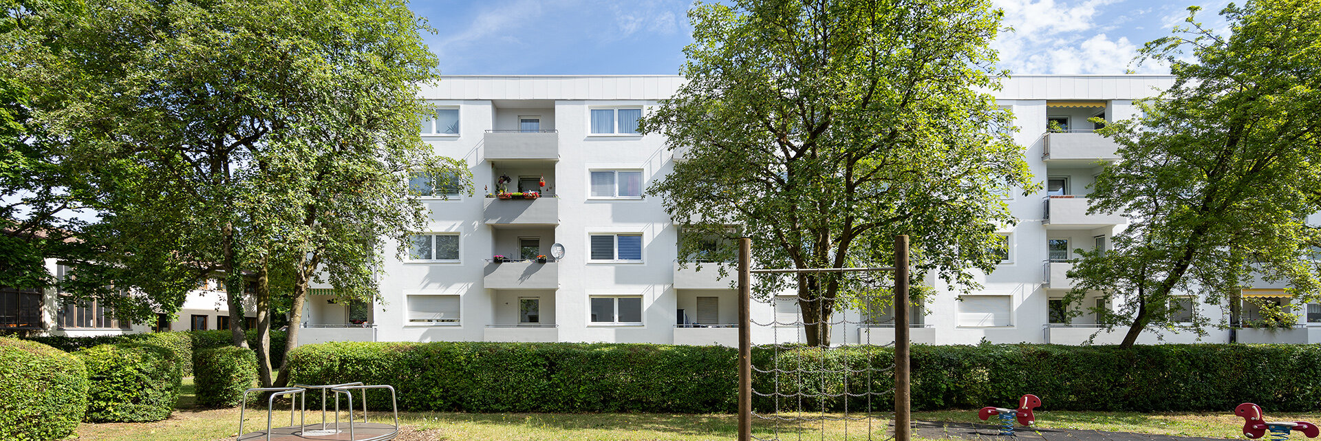 Wohngebäude mit Balkonen ausgerichtet auf eine Grünanlage mit Spielplatz