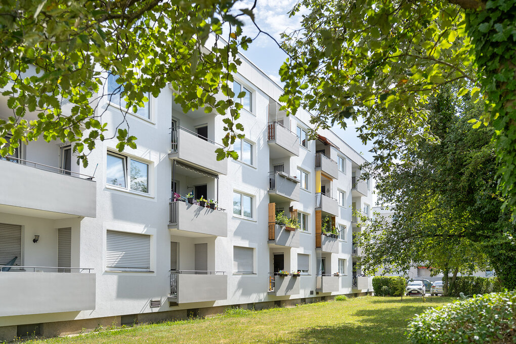 Rückseite des Wohngebäudes mit Balkonen und Blick ins Grüne 
