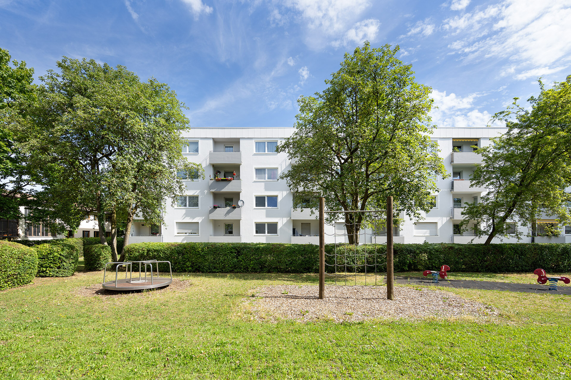 Wohngebäude mit Balkonen ausgerichtet auf eine Grünanlage mit Spielplatz