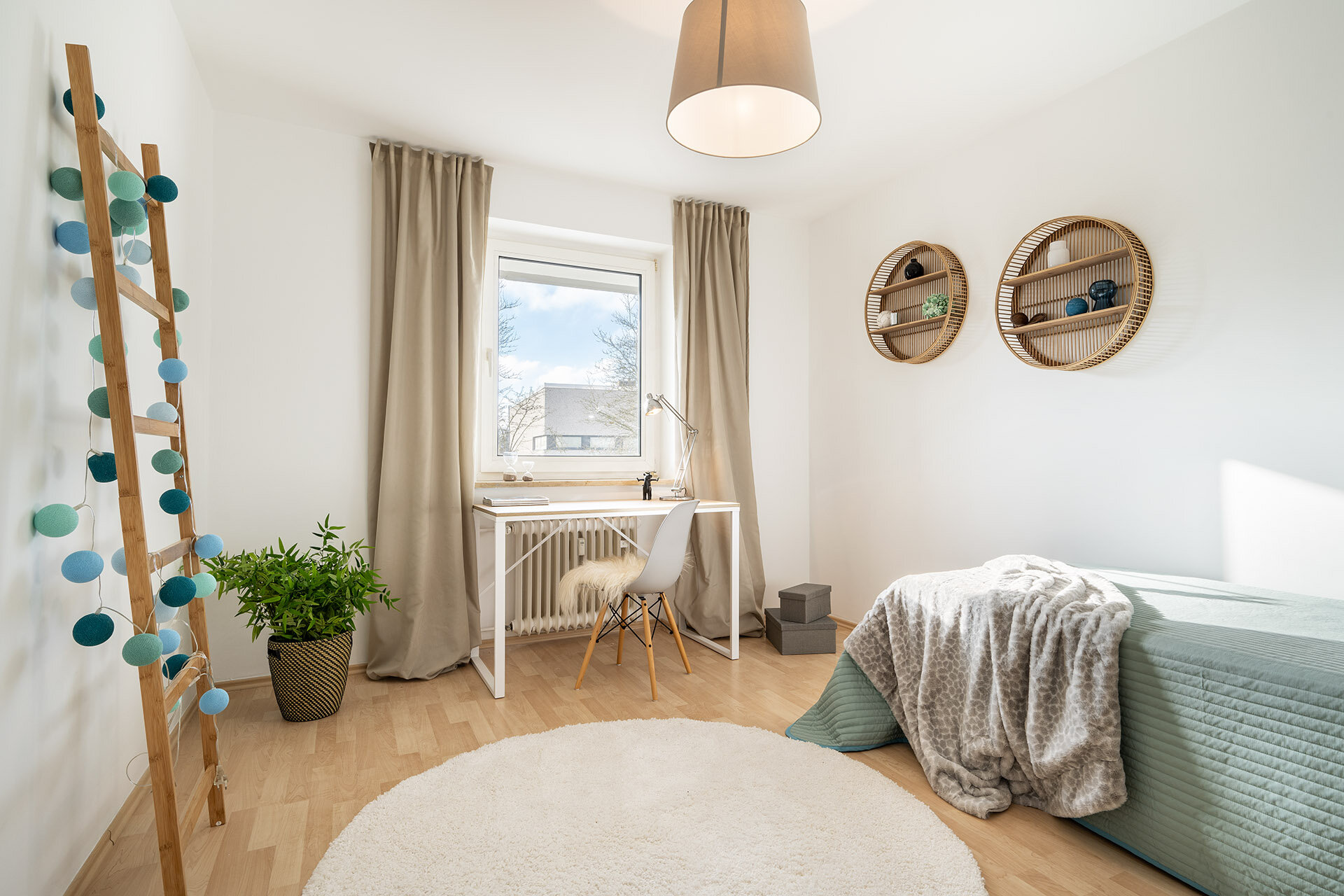 Helles Kinderzimmer mit Einzelbett und Schreibtisch vor dem Fenster
