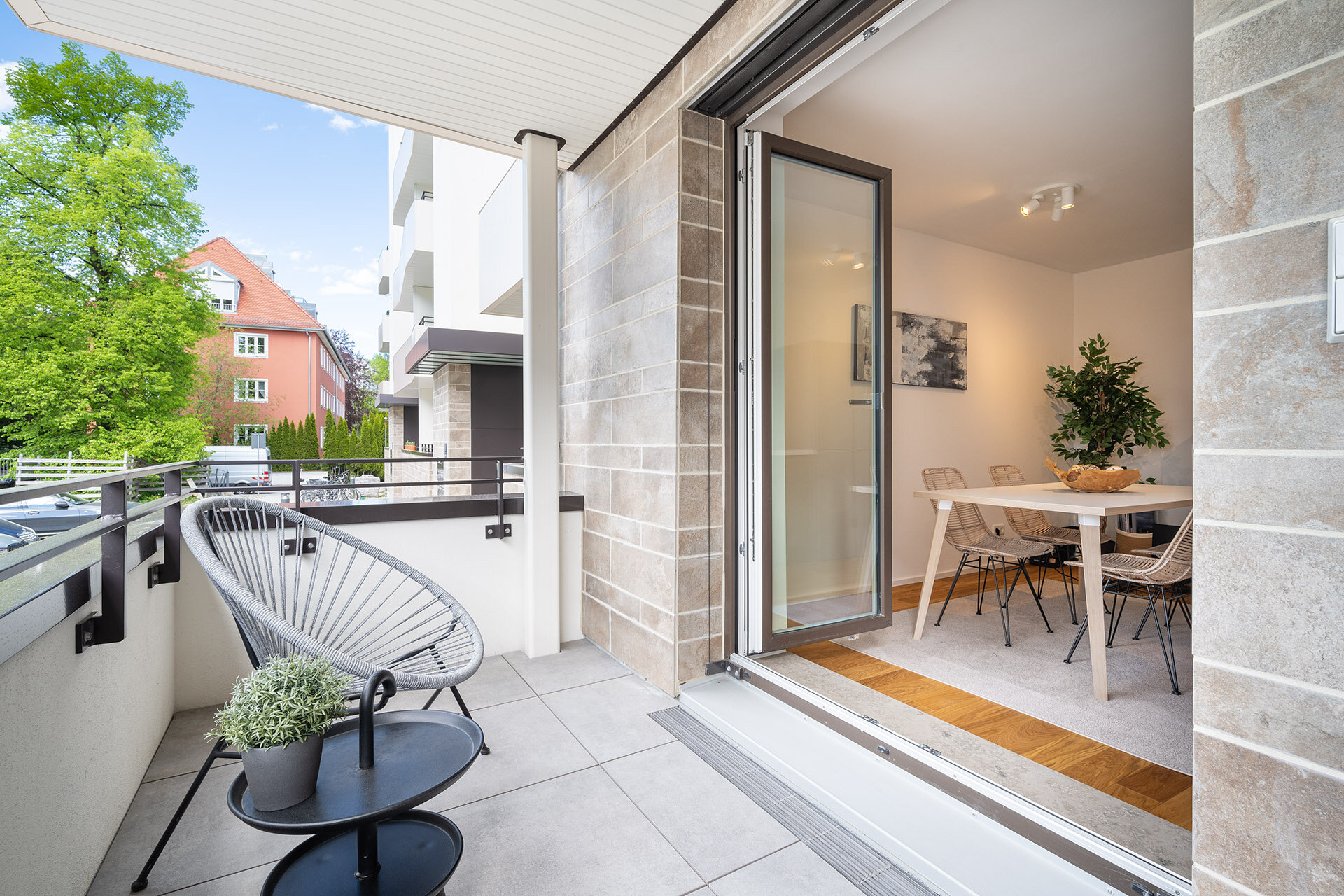 Blick vom Balkon auf die Küche mit Esstisch, im Vordergrund ein Balkonsessel.