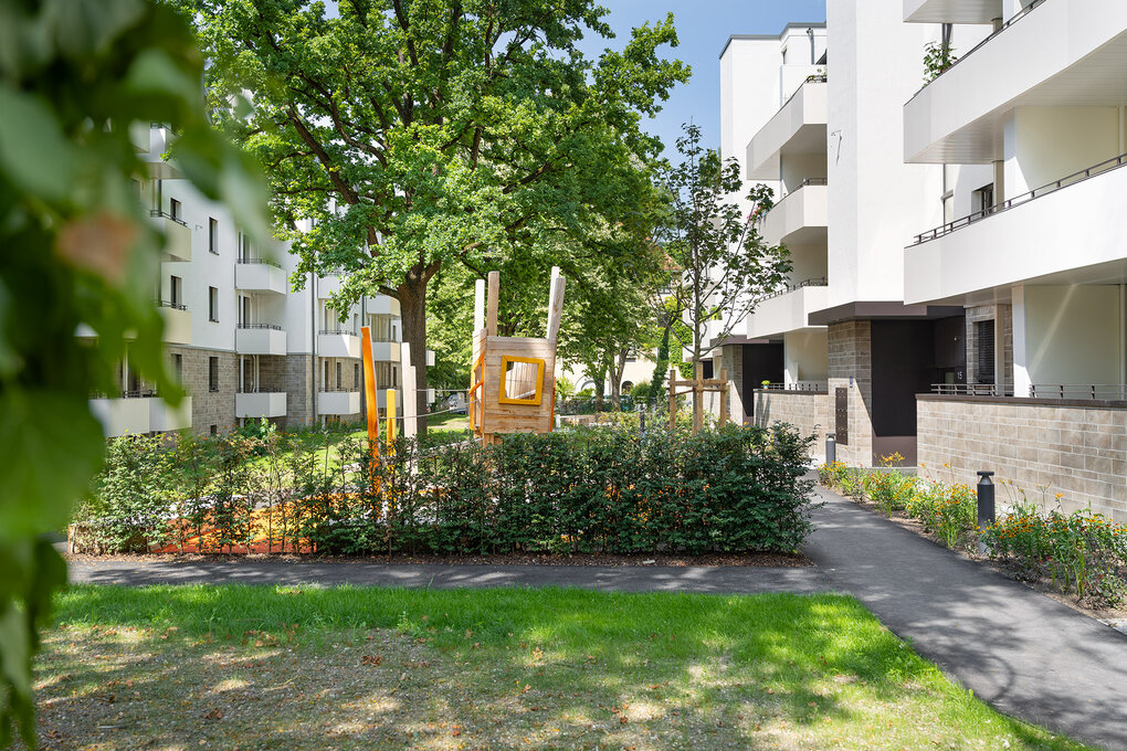 Innenhof Ansicht mit Grünanlage und Spielplatz zwischen den modernen Wohnhäusern des Noya Komplex