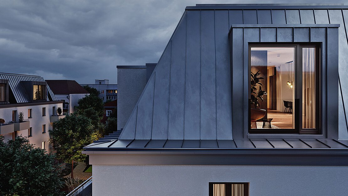 Außenansicht Eckzimmer der NOYA Dachgeschosswohnung am Abend mit Blick in die beleuchtete Wohnung
