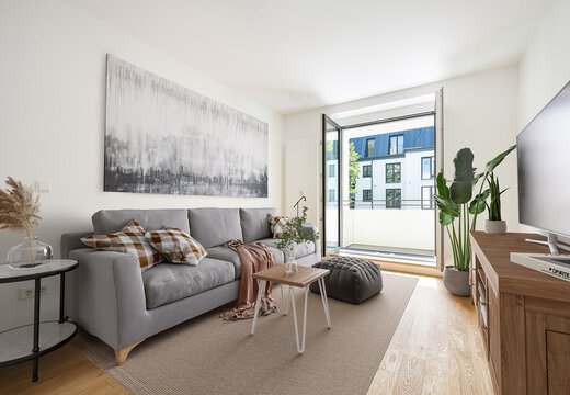 Kleines sehr modernes Wohnzimmer und offener Balkontür. Klassisch moderne Einrichtung mit grauem Sofa, Beistelltisch, Kommode und Fernsehen sowie Zimmerpflanze