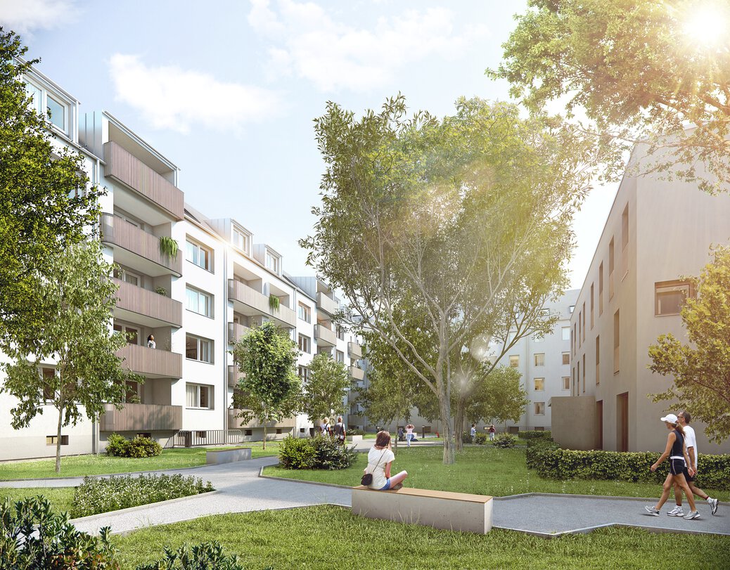 Grüner Innenhof der BLUS Wohnanlage mit Parkbänken und Blick auf Balkone
