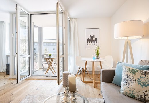 Helles freundliches Wohnzimmer mit offenen Balkontüren. Schlichte moderne Einrichtung