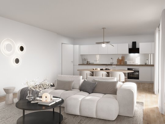 Ein modernes Wohnzimmer mit offener Küche. Im Vordergrund steht ein großes weißes Ecksofa um einen runden schwarzen Couchtisch. Im Hintergrund ist eine helle, minimalistische Küche mit weißen Schränken und dunkler Arbeitsplatte zu sehen. Ein Deckenventilator hängt über dem Esstischbereich.