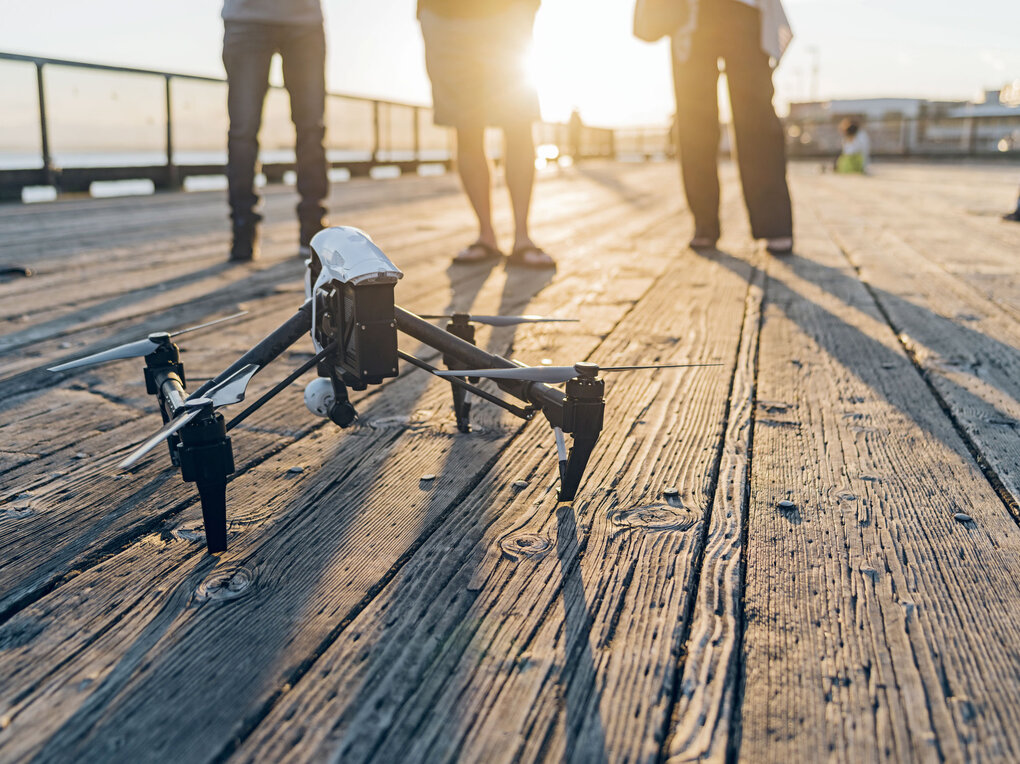 Drohne auf einem Holzsteg bei Sonnenuntergang – Symbolbild für technologische Innovation und Agilität
